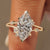 Split shank engagement ring with marquise diamond and round side stones.
