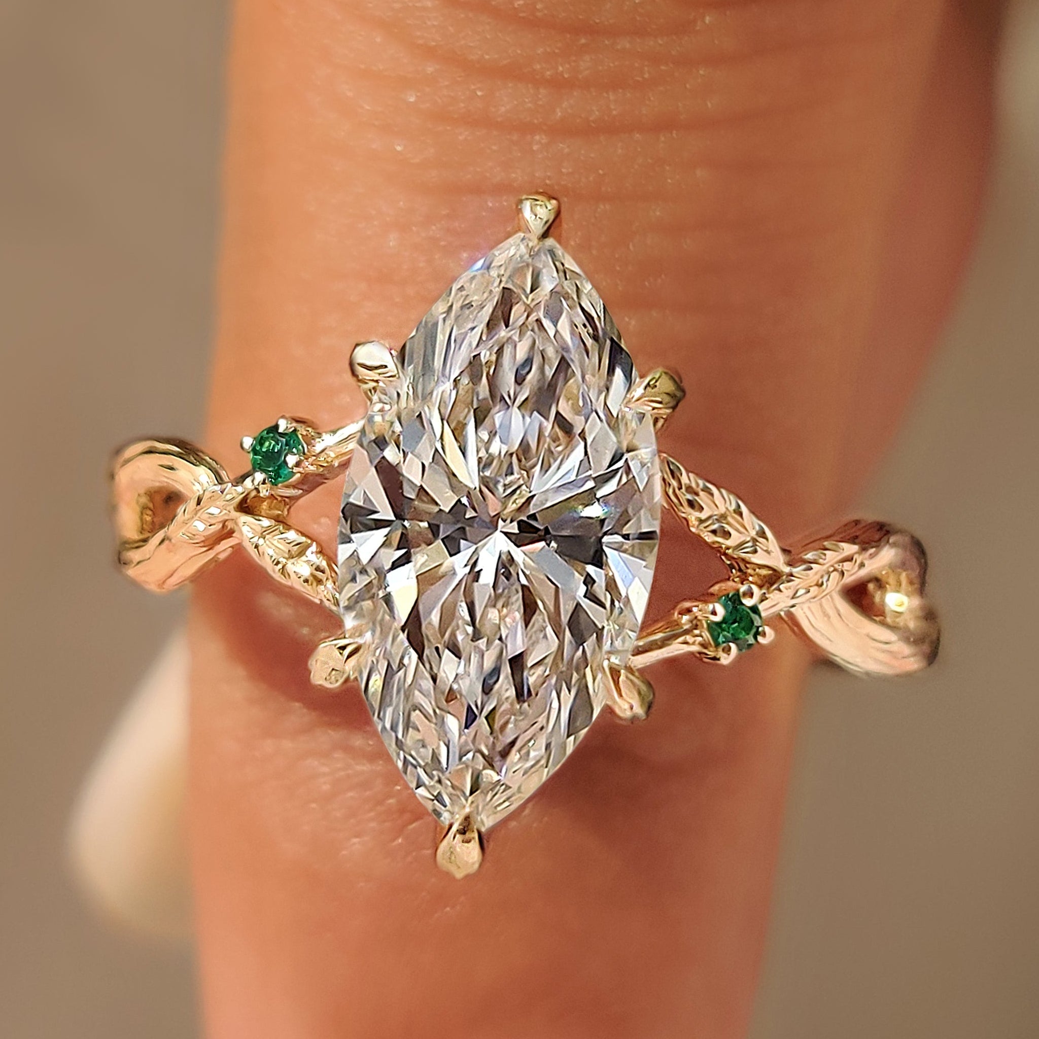 Marquise ring with round green emerald gemstone accents.
