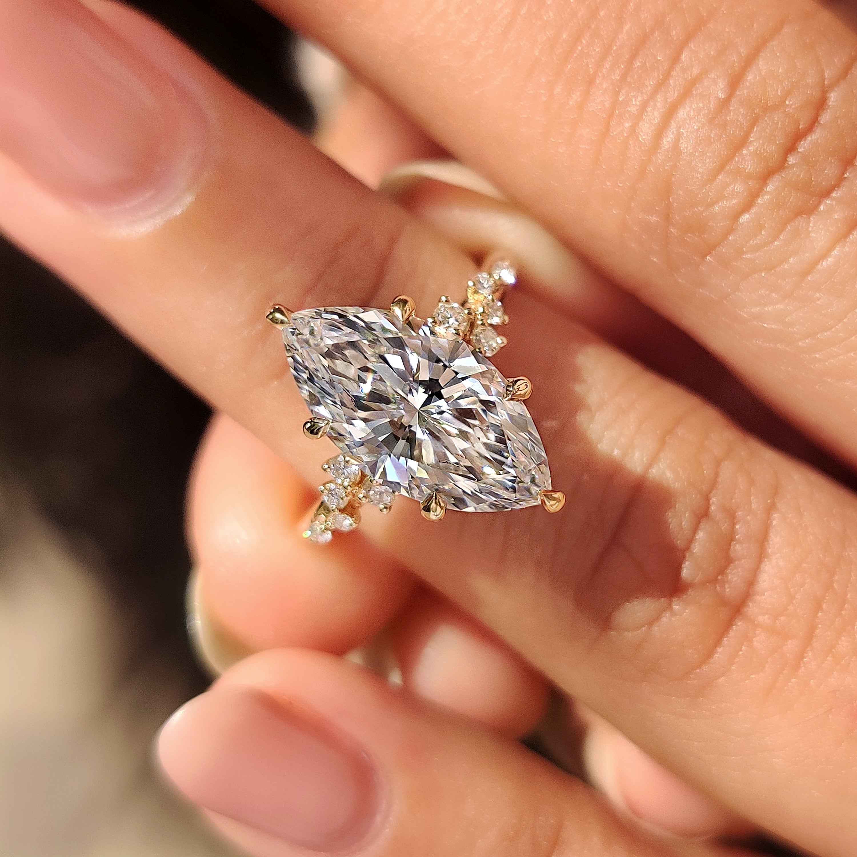 Marquise cut engagement ring glows with round side stones and claws.
