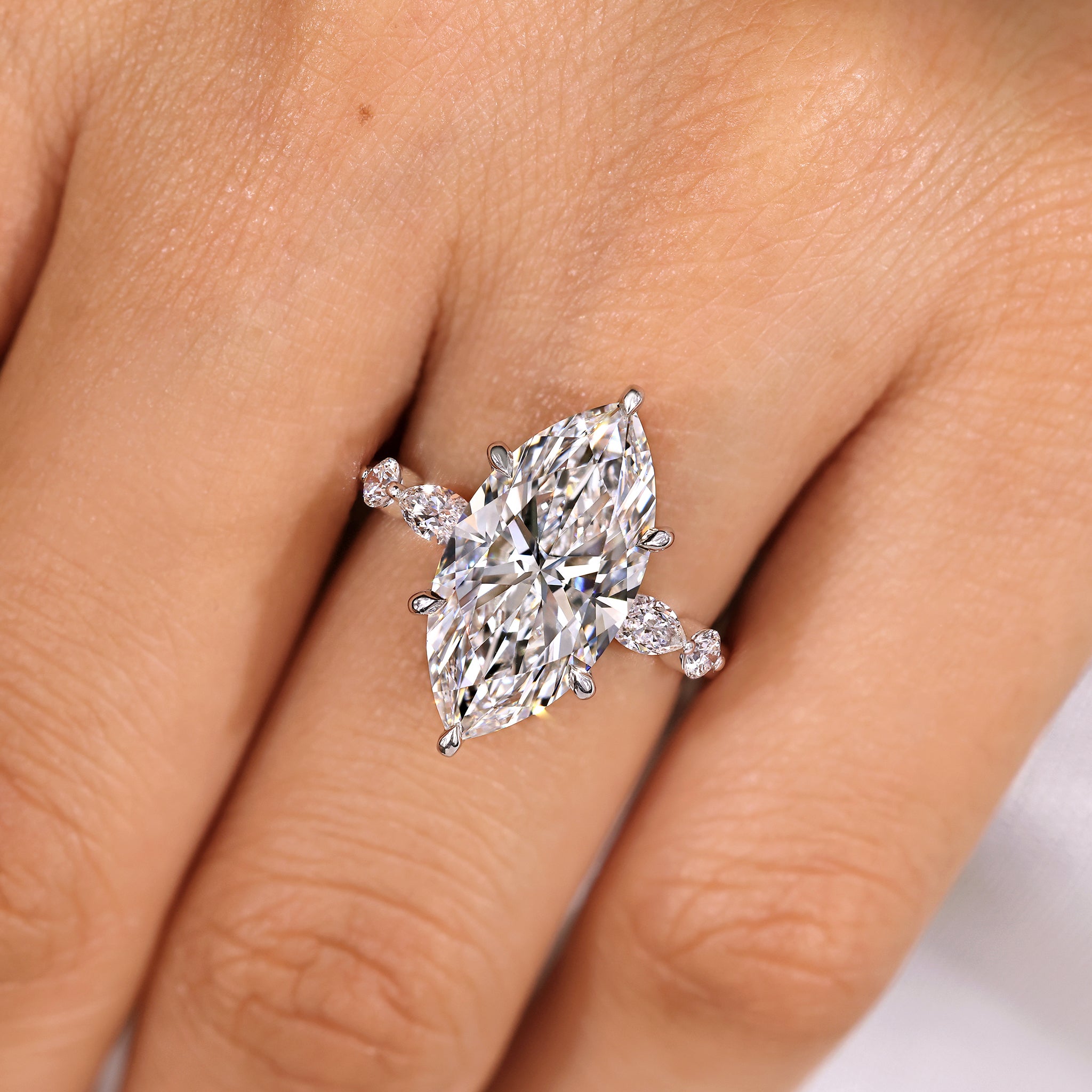 Marquise diamond ring with round side stones and shared prong
