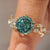Portuguese cut cyan blue moissanite ring with leaf details.
