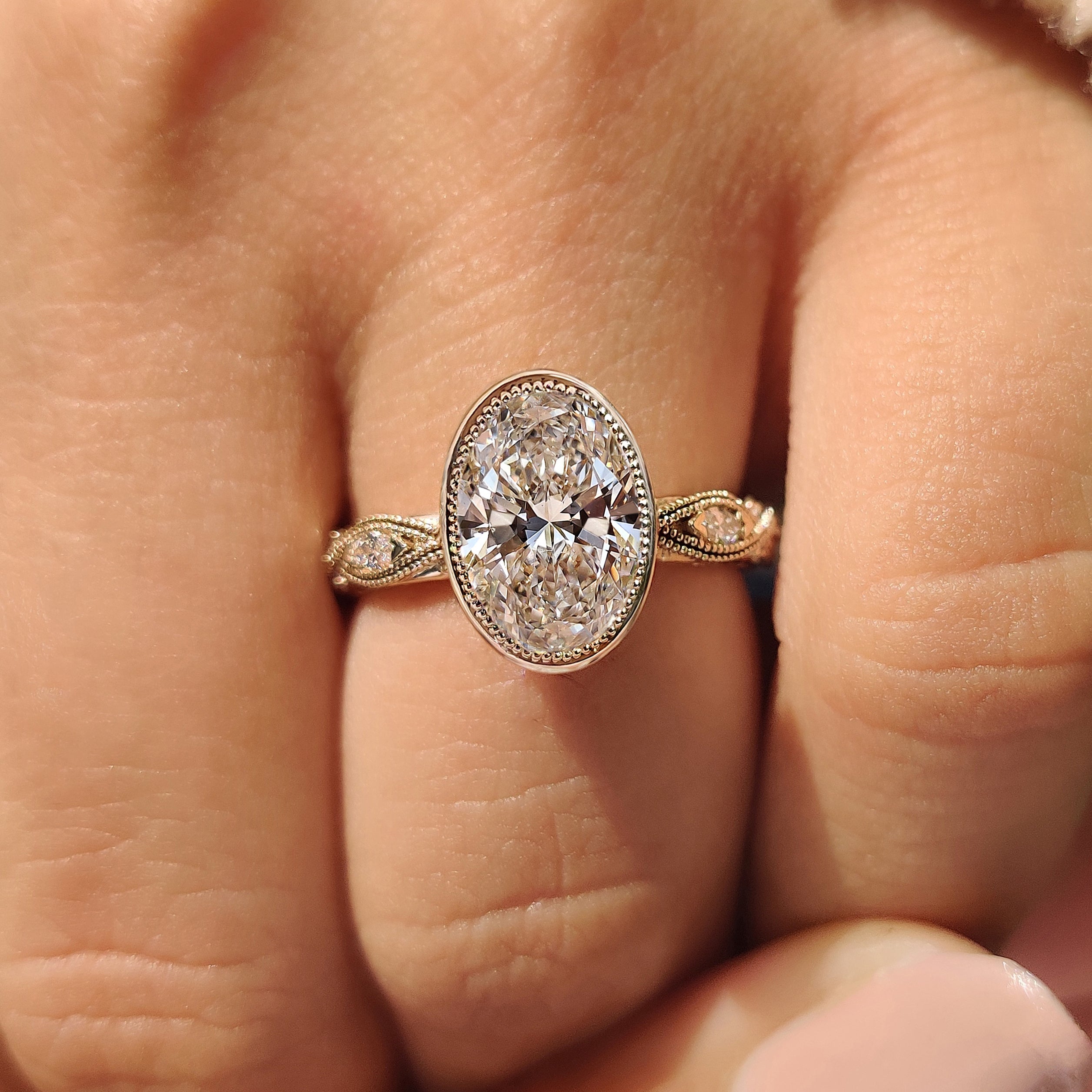 Oval bezel engagement ring with milgrain details
