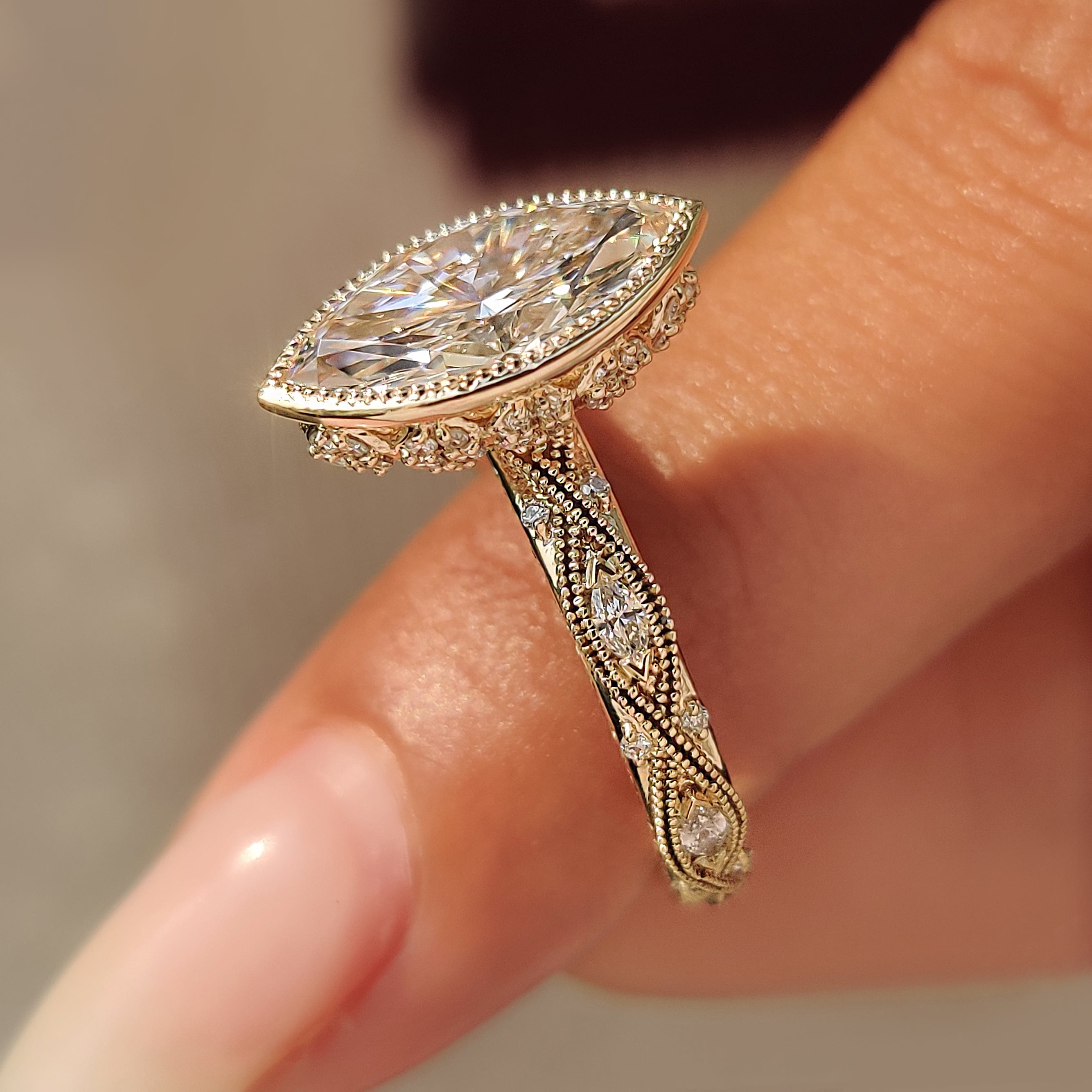 Decorative floral basket below a marquise cut center diamond.
