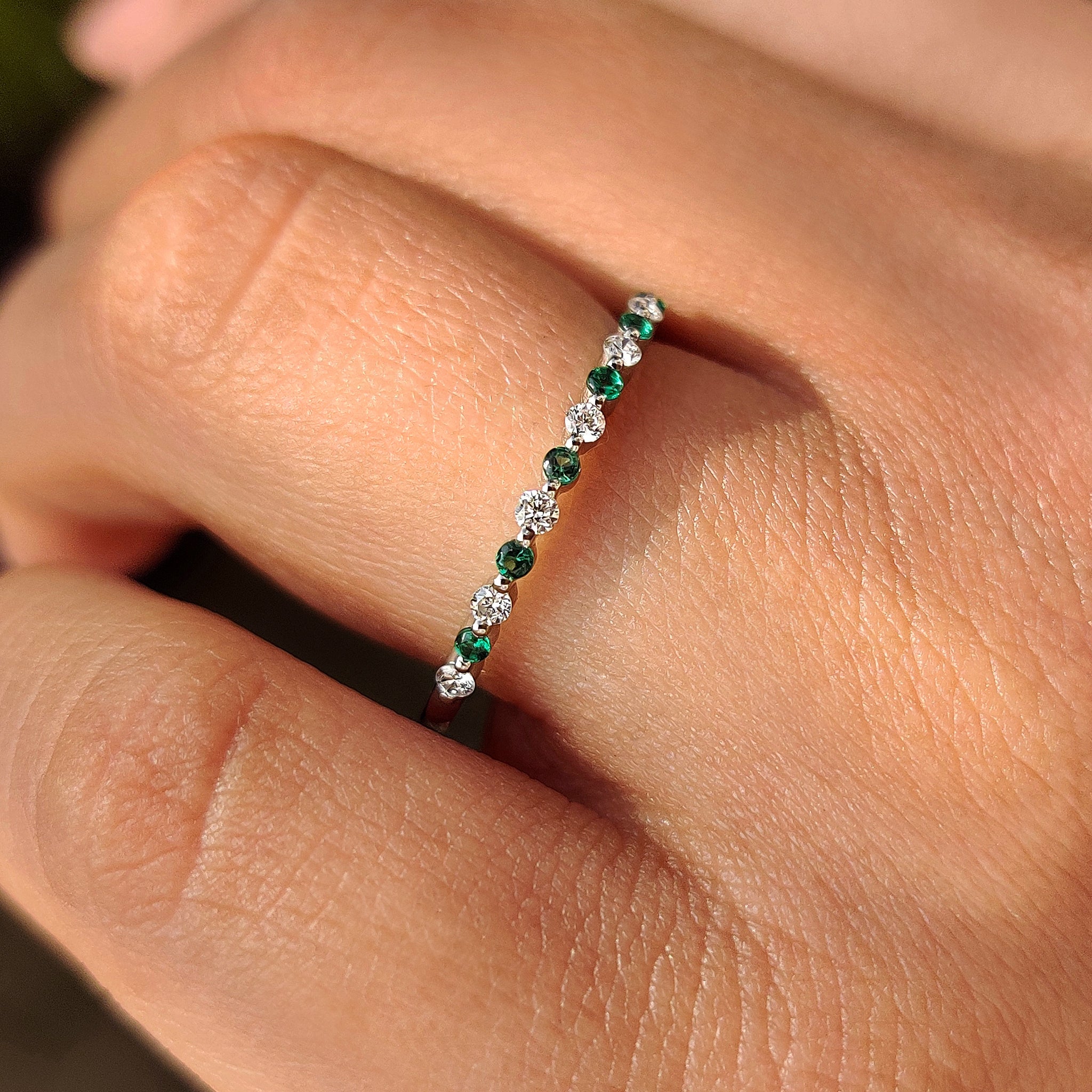 Half eternity band shared prong diamond and emerald gemstone.
