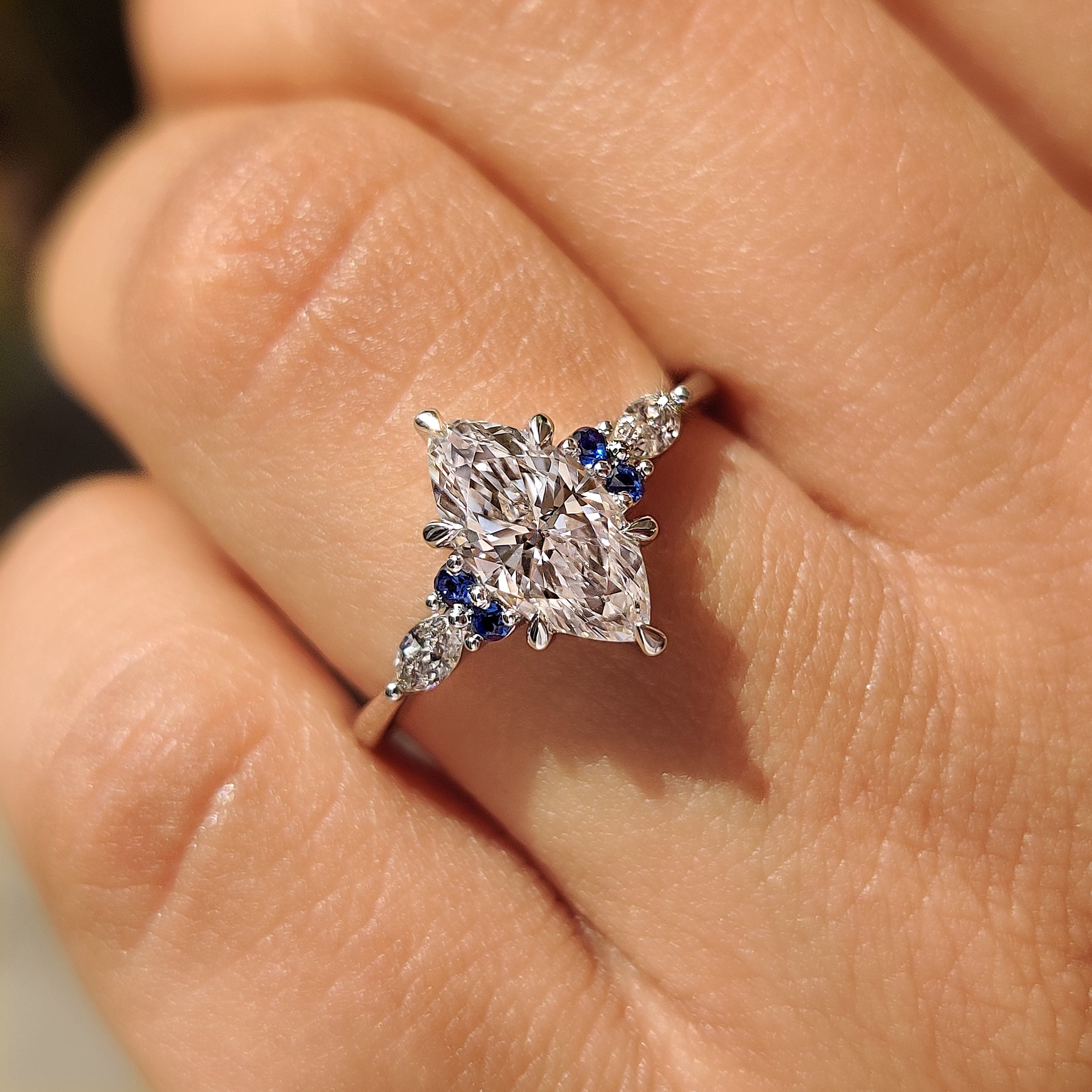 Marquise engagement ring with round sapphire side stones design
