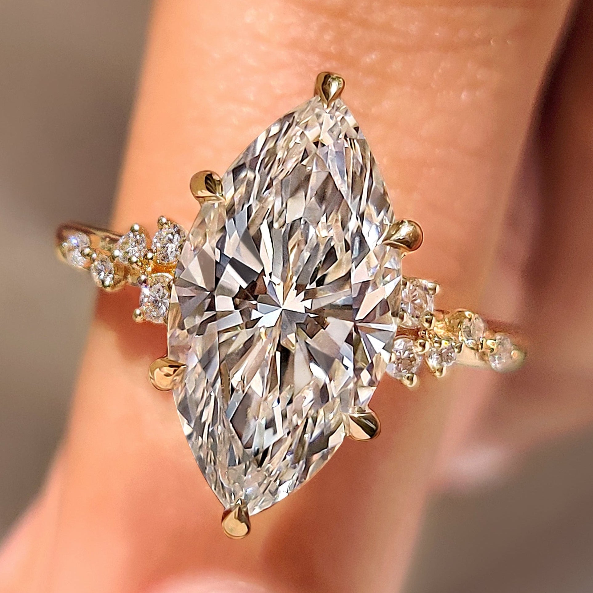 Marquise cut engagement ring sparkles with cluster setting and round stones.
