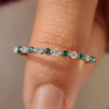 Half eternity band with round diamond and emerald gemstone.
