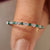 Half eternity band with round diamond and emerald gemstone.
