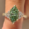 Green marquise diamond cluster ring with floral band.
