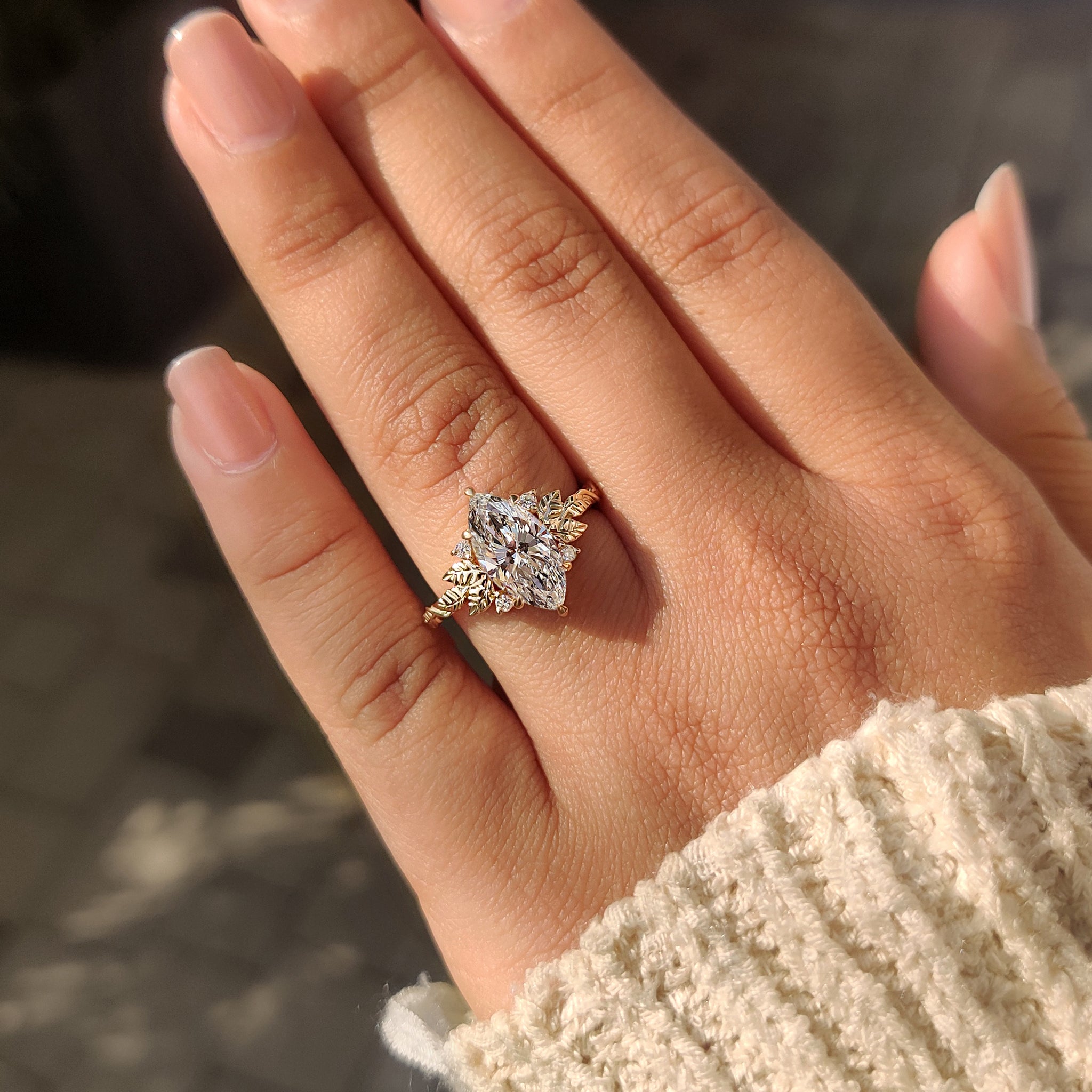 Marquise engagement ring with round side stones and leaf accents.
