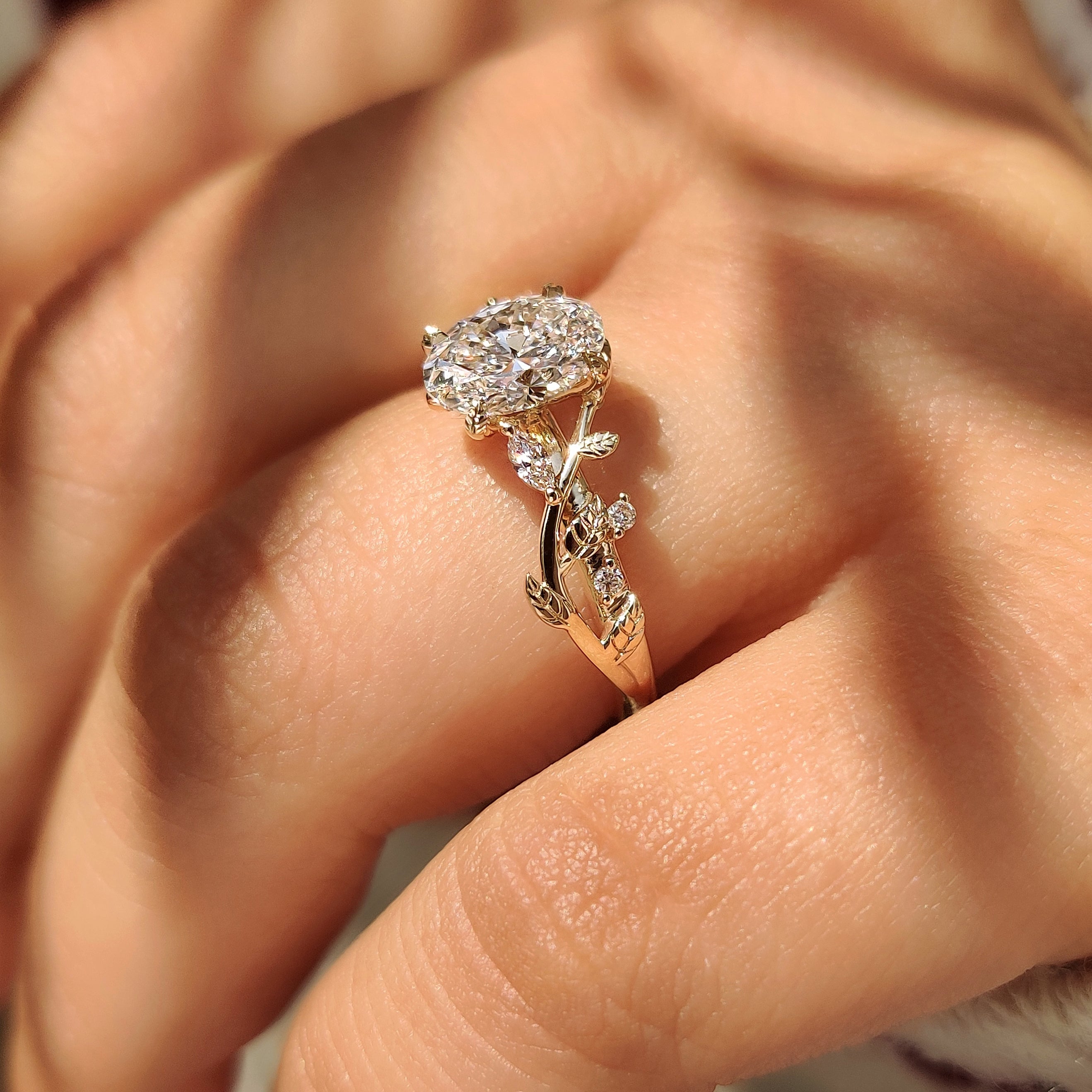 Handmade oval diamond ring with vine and leaf accents.
