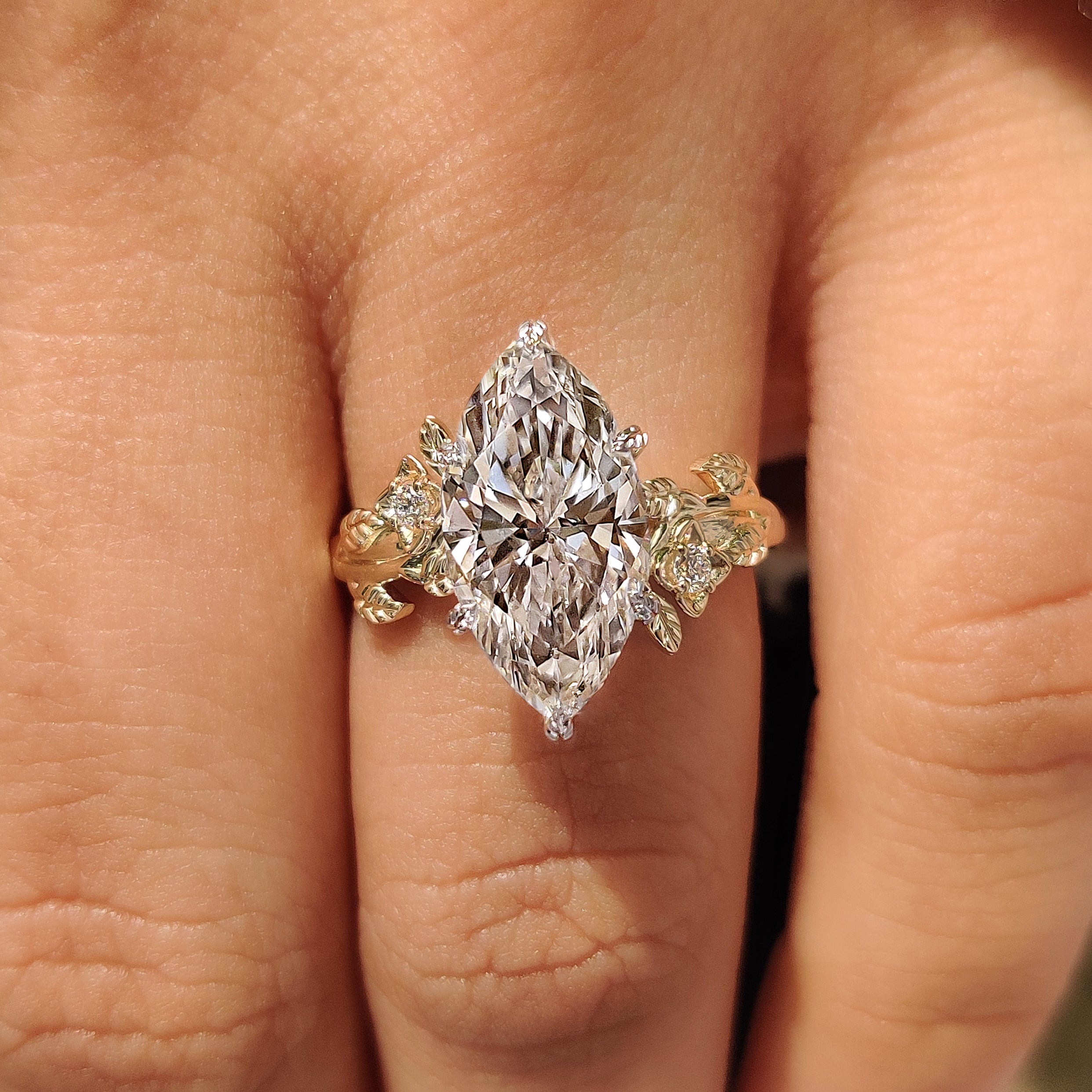 Marquise center diamond with six claw prong setting in two tone ring
