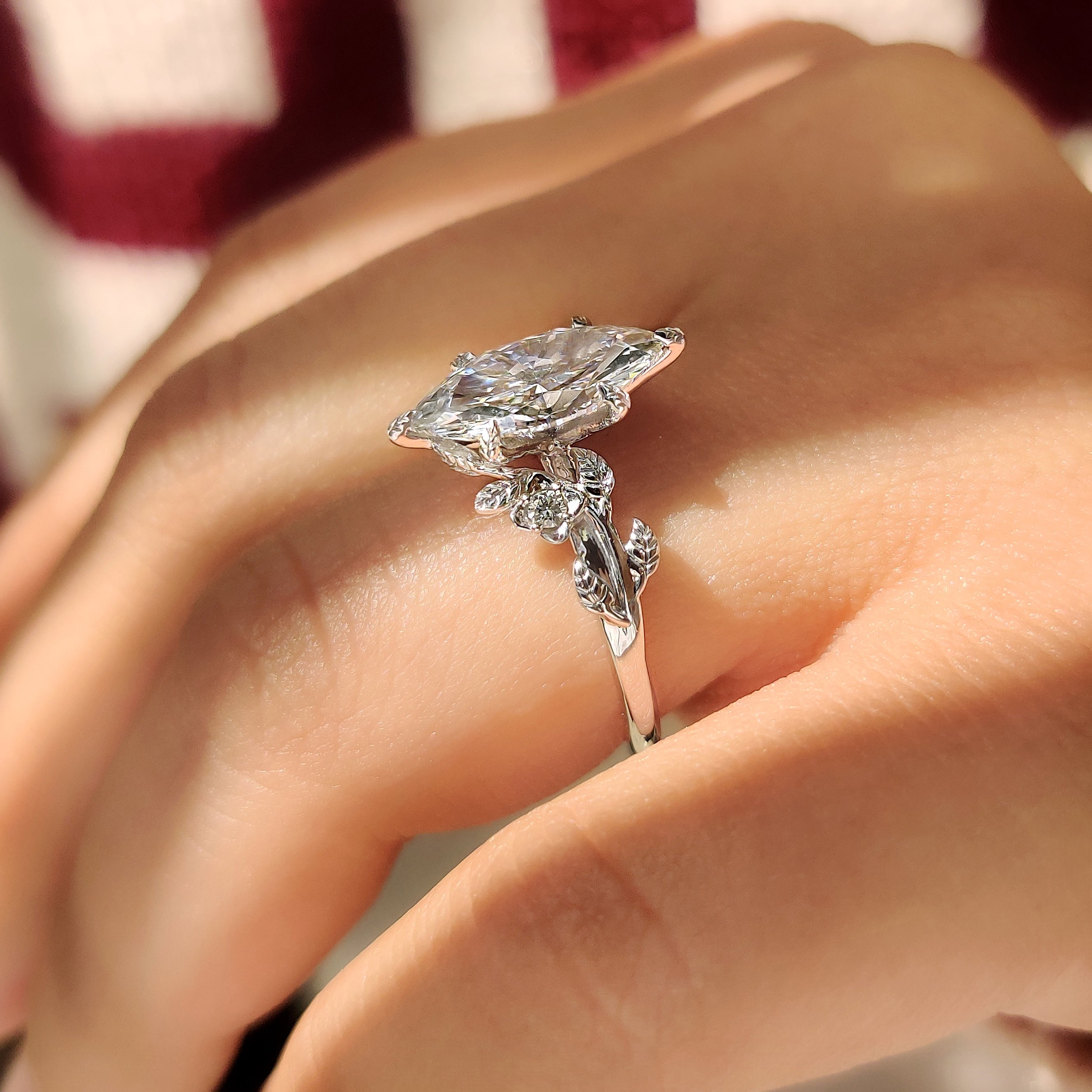 Marquise engagement ring with floral details and cluster setting.
