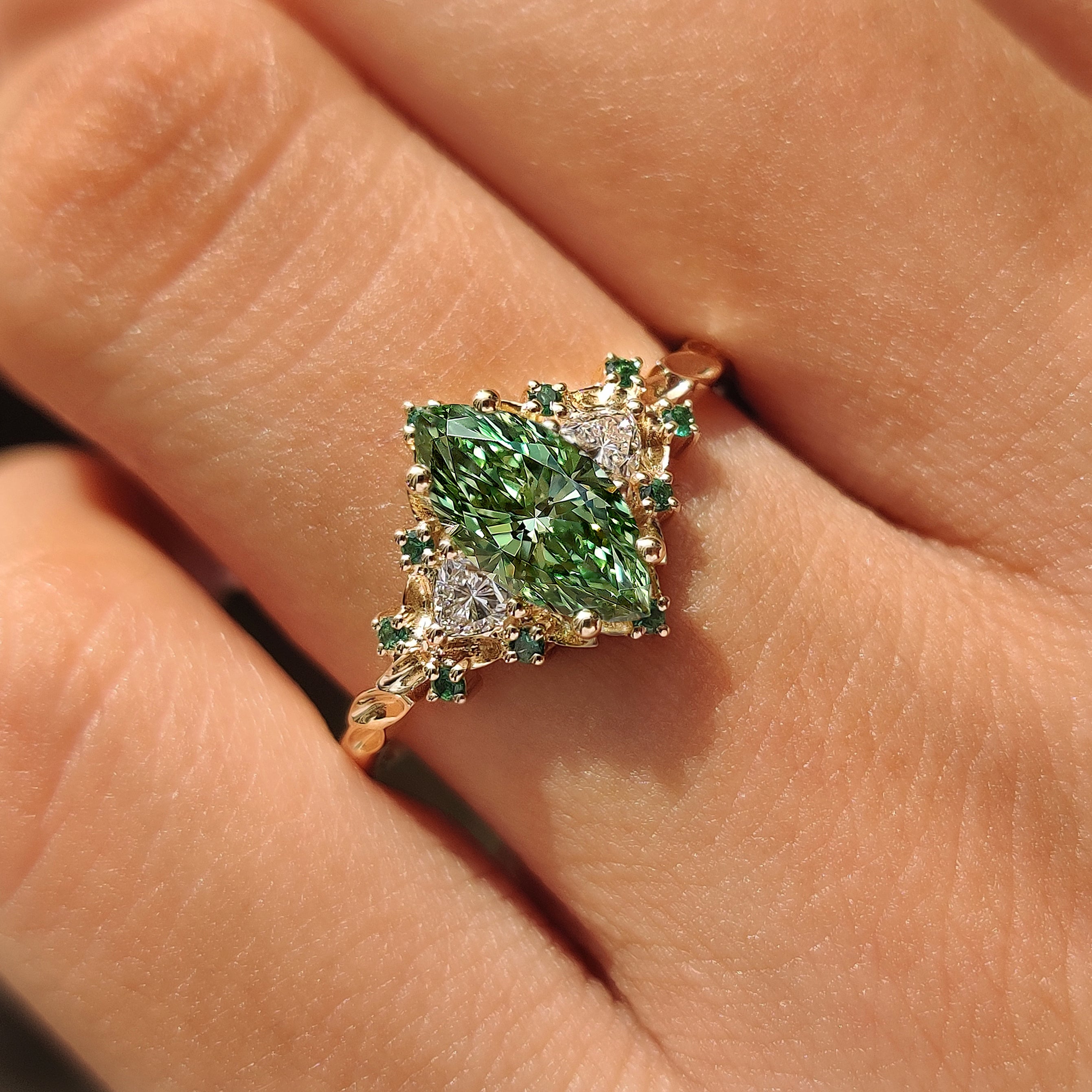 Green marquise diamond ring with emerald accents.
