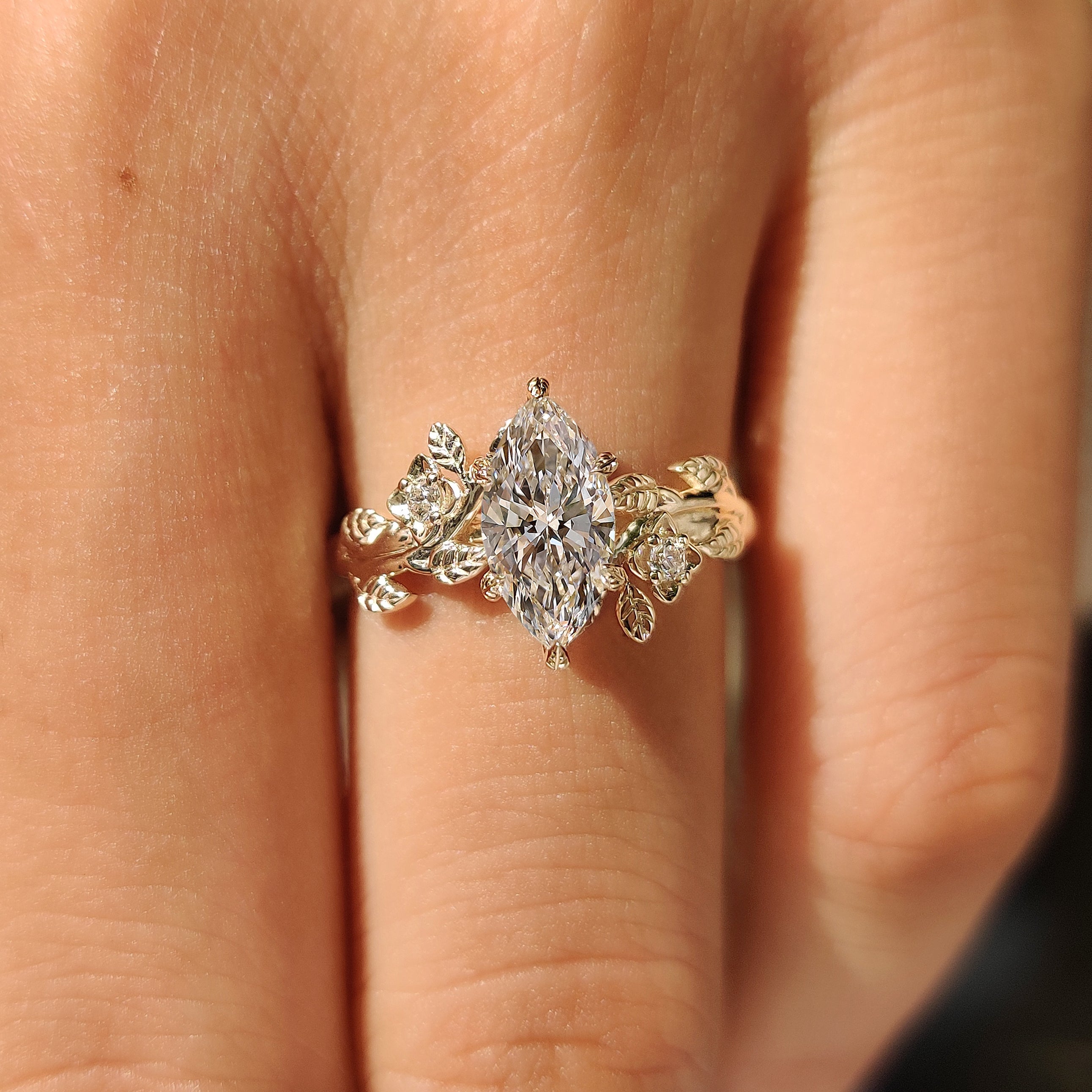 Marquise diamond ring with round accents and leaf details
