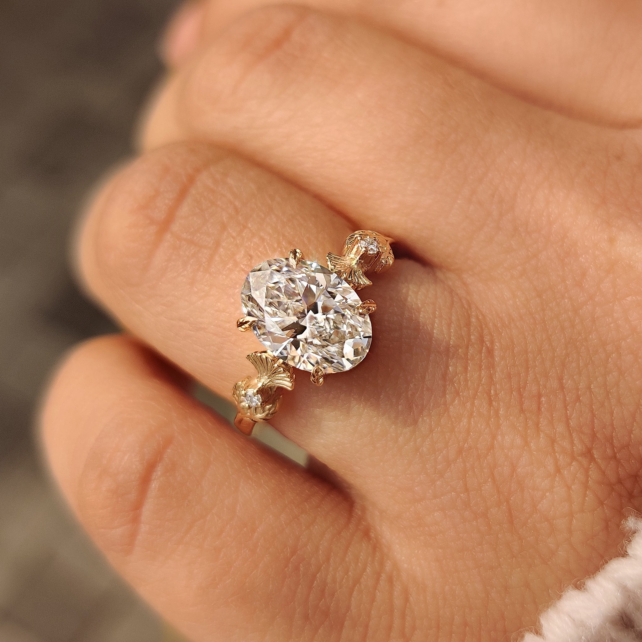 Oval diamond ring with round side stones and leaf prongs
