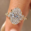 Oval diamond ring with cluster setting and round side stones.
