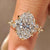 Oval diamond ring with cluster setting and round side stones.
