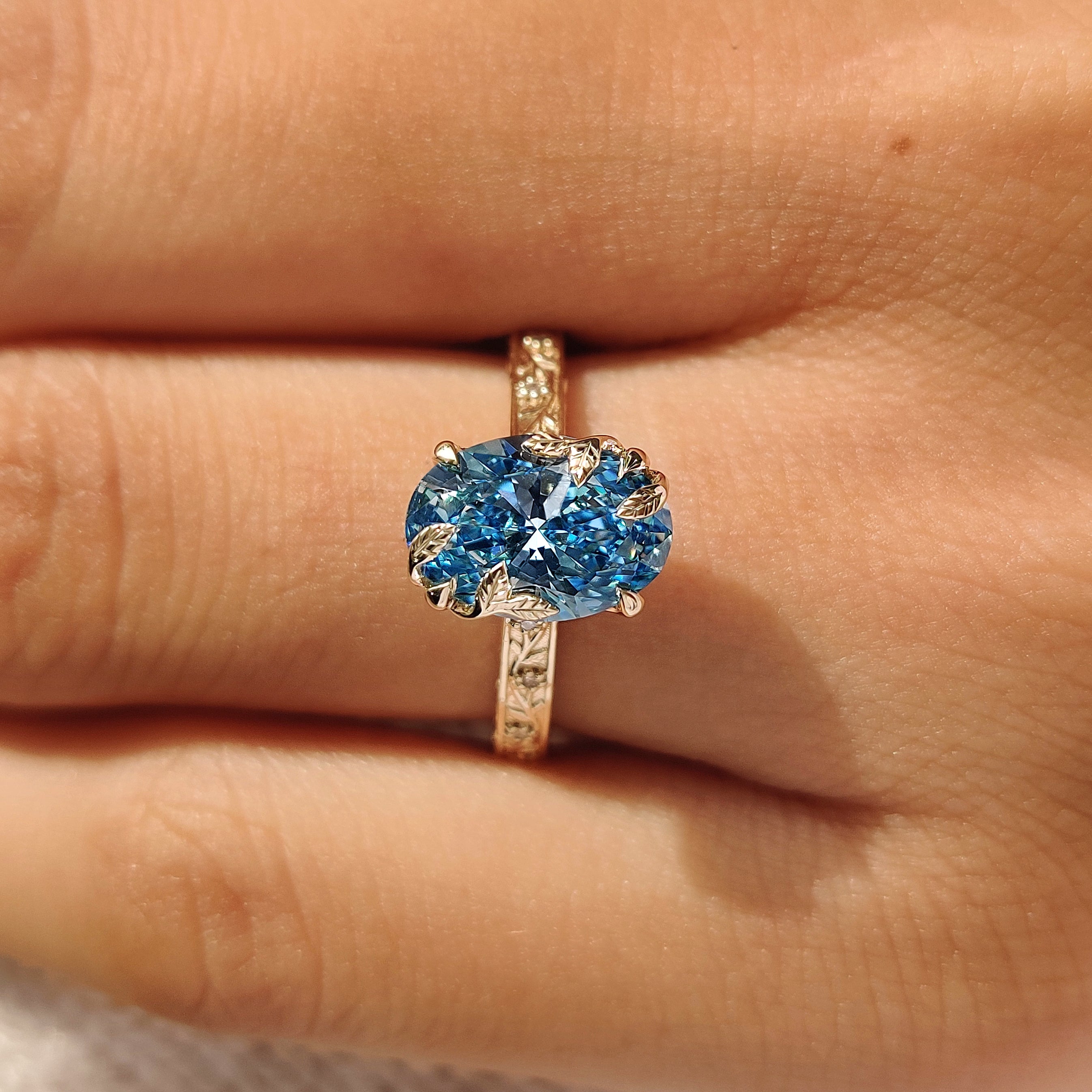 Blue oval diamond ring with round diamond accent
