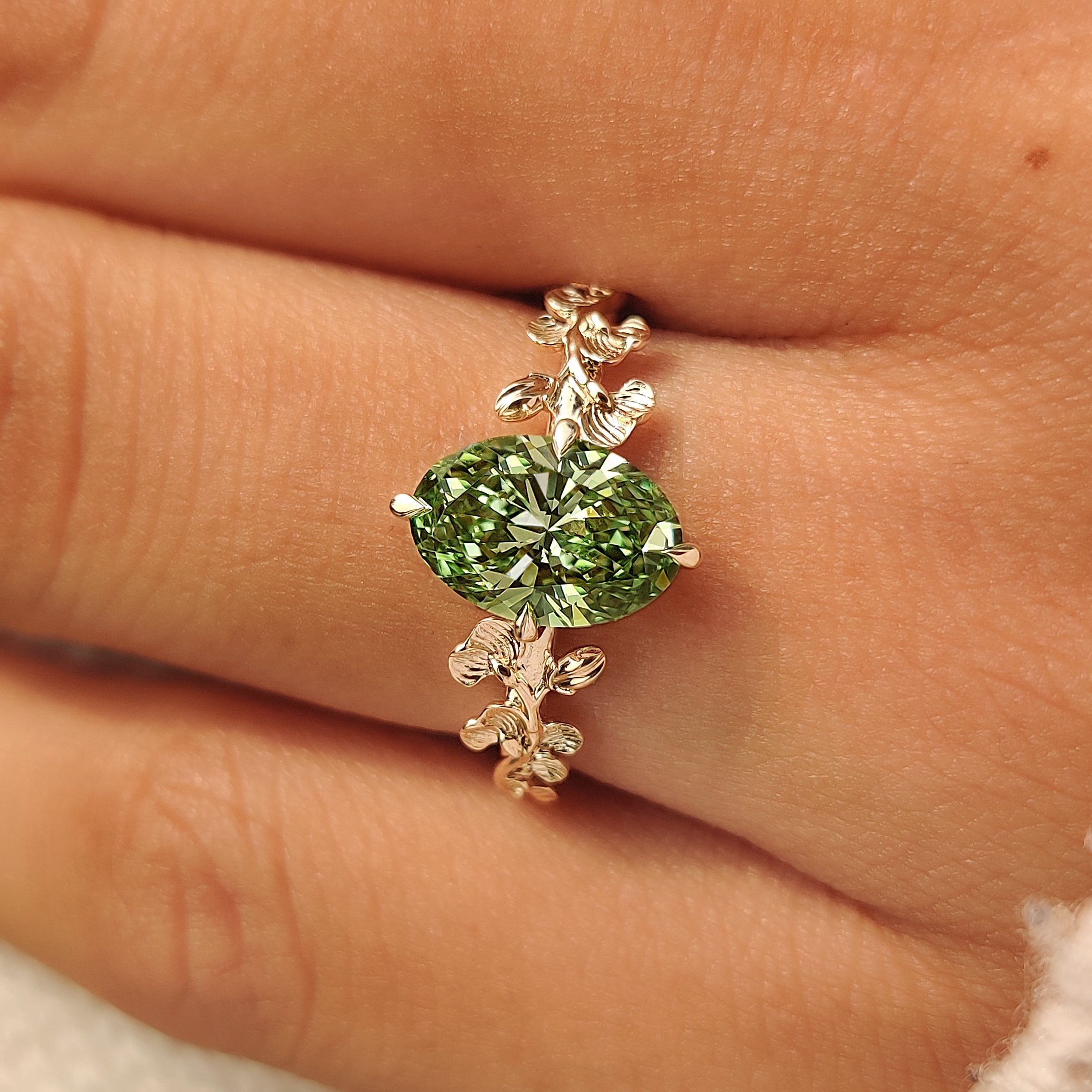 Green oval diamond secured by compass prongs.
