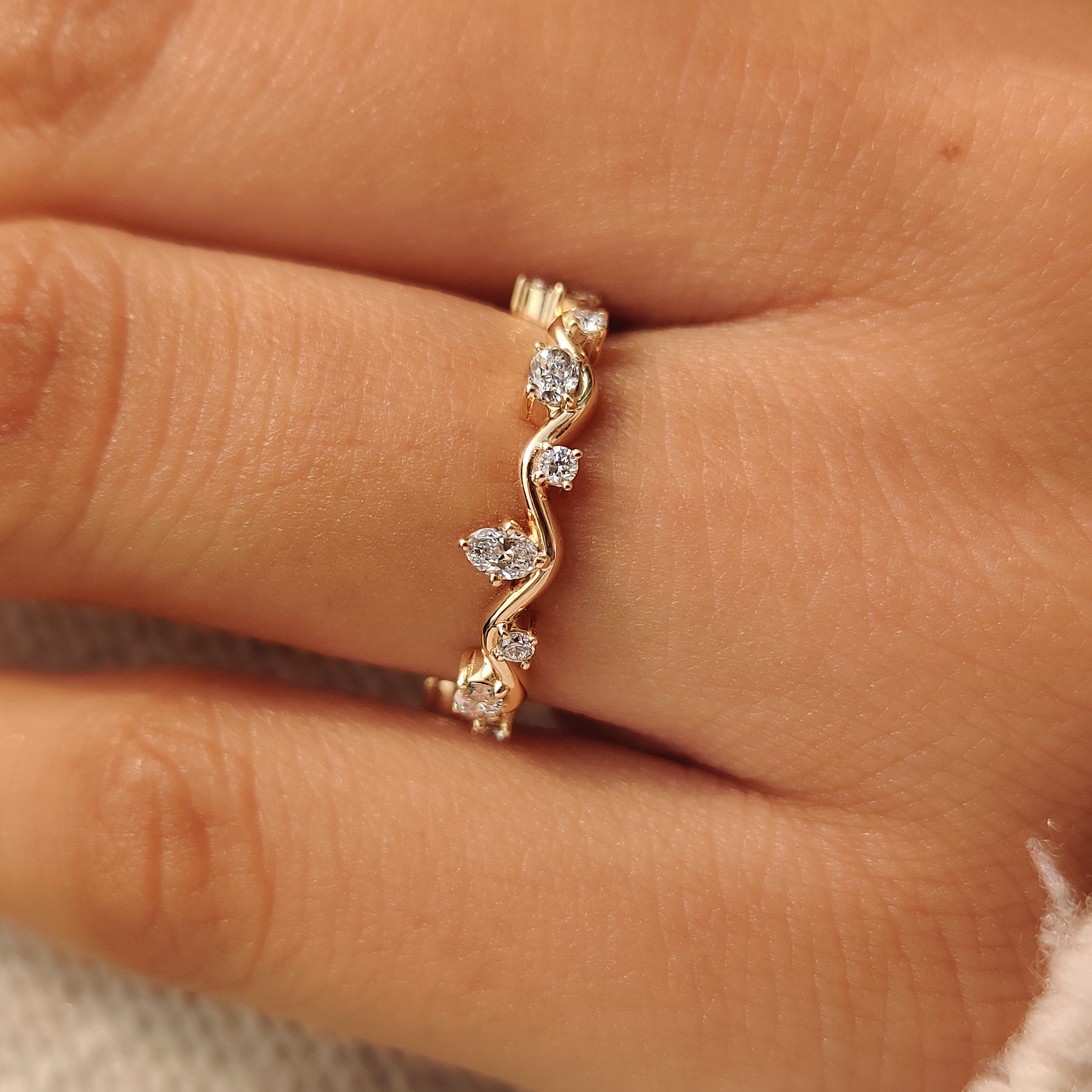 Fluid wave band design with oval and round diamonds.
