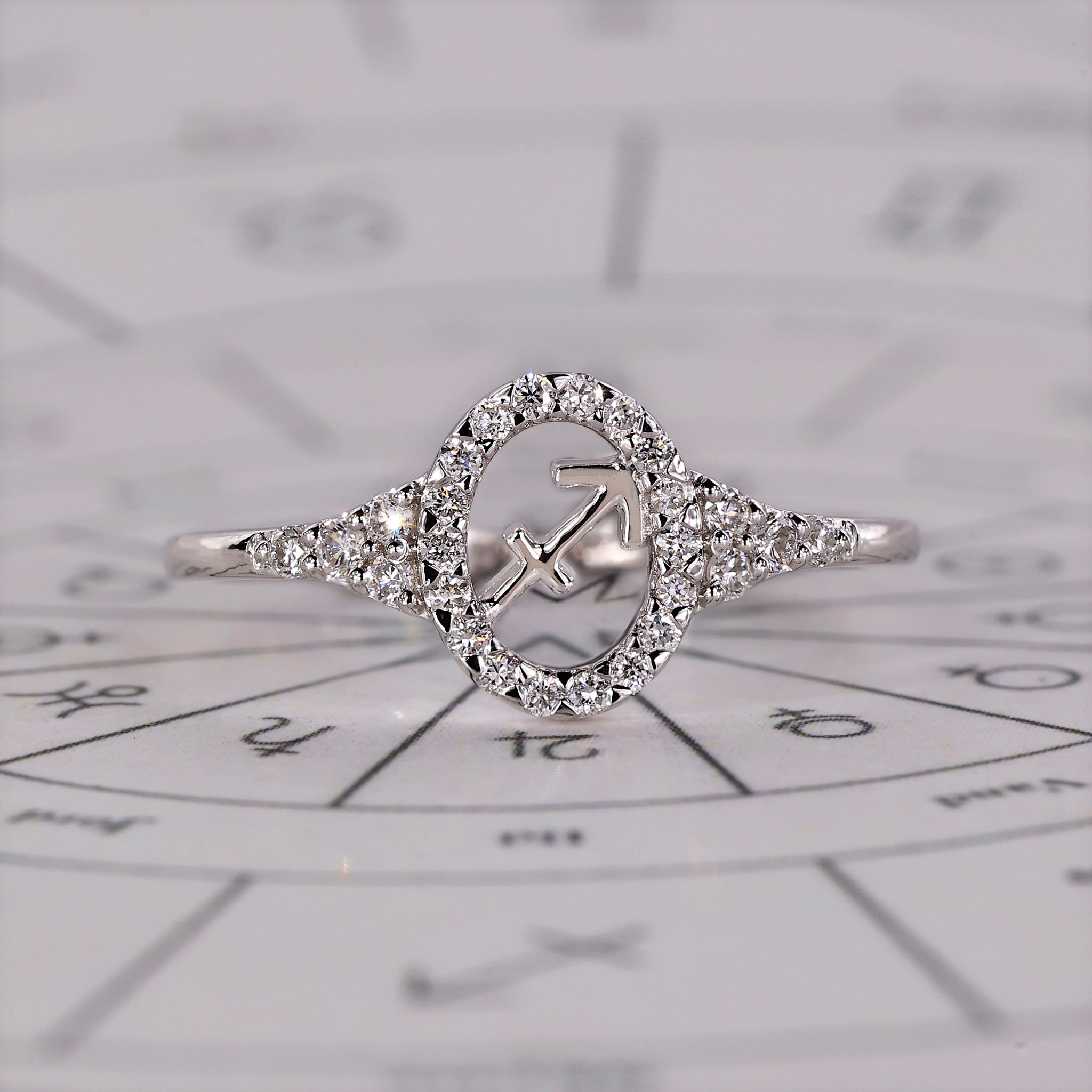 Sagittarius ring in white gold with halo engagement and round side stones.
