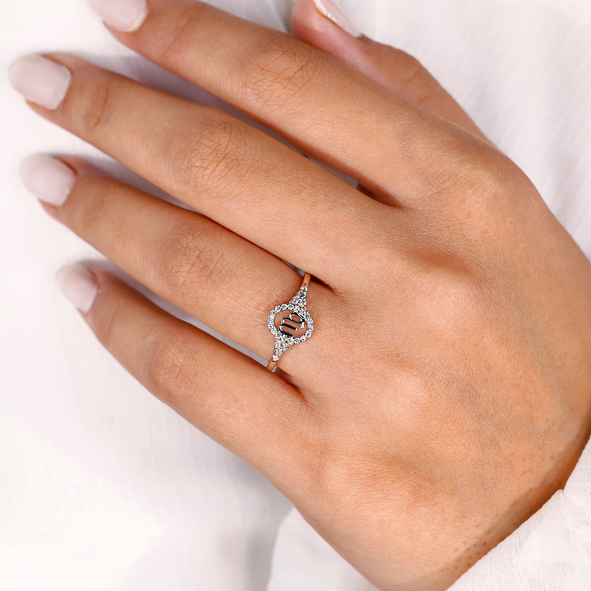 Gold Virgo ring with halo diamond and round side stone detailing.
