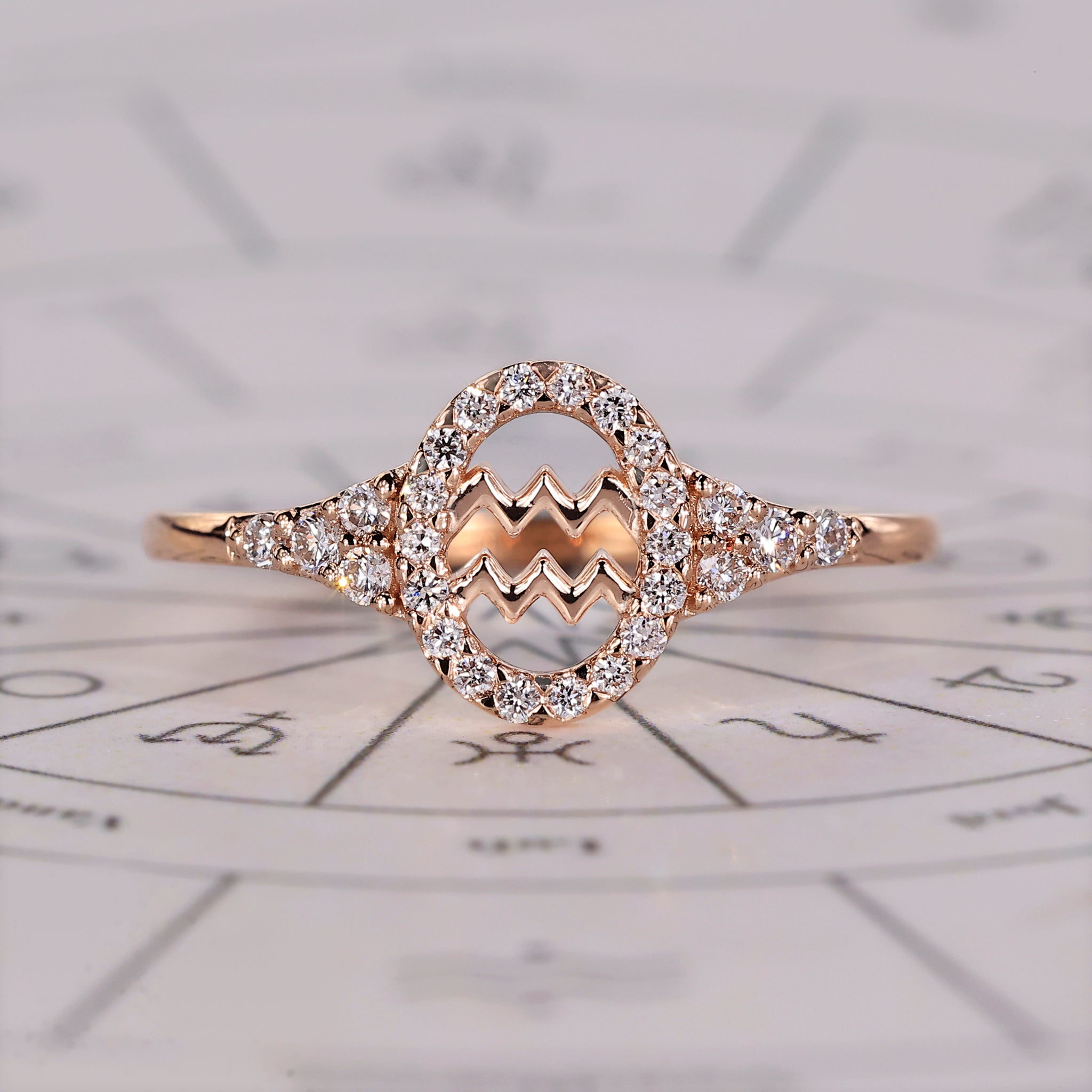 Aquarius ring with round side stone and halo diamond in rose gold.

