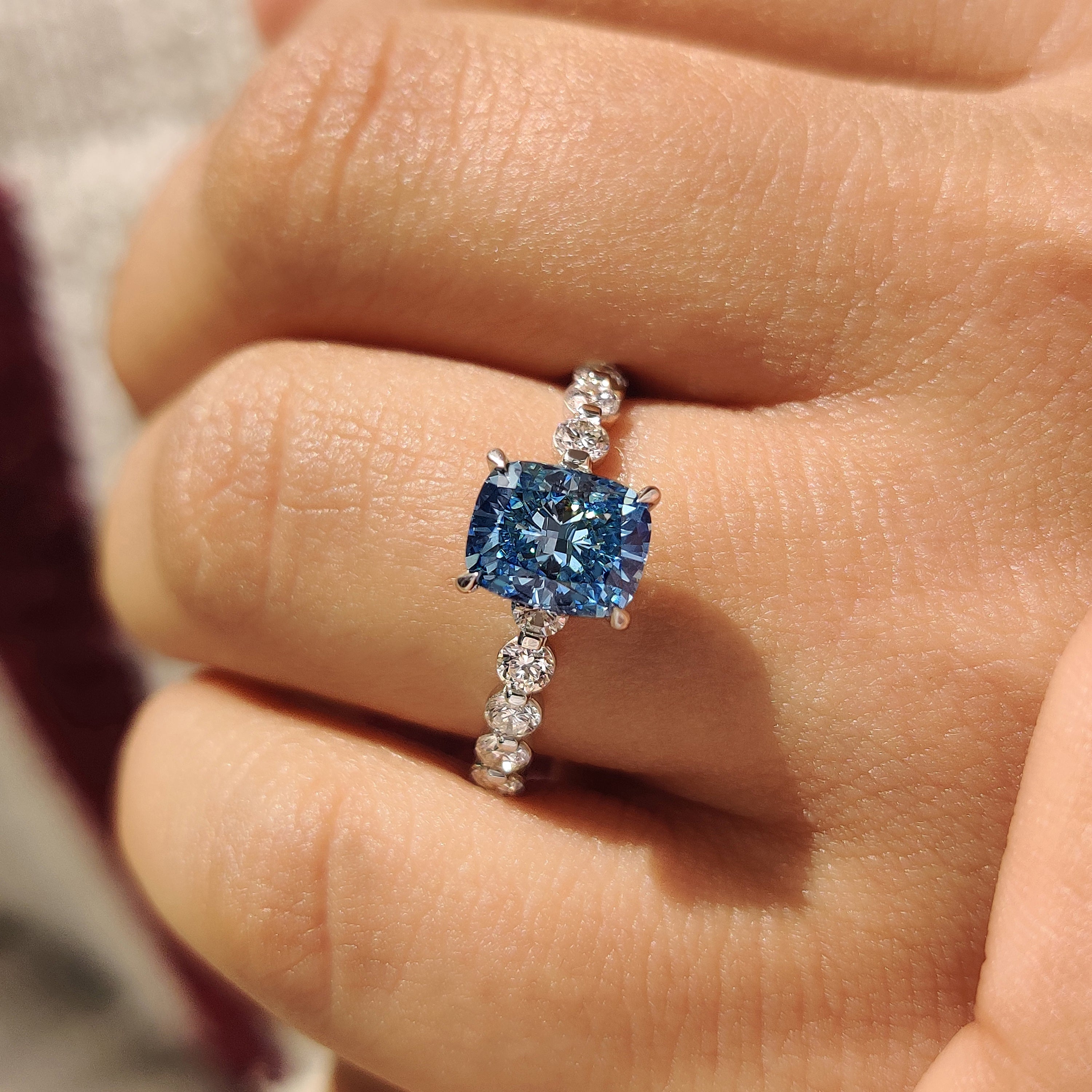 Blue diamond ring with four claw prong setting.
