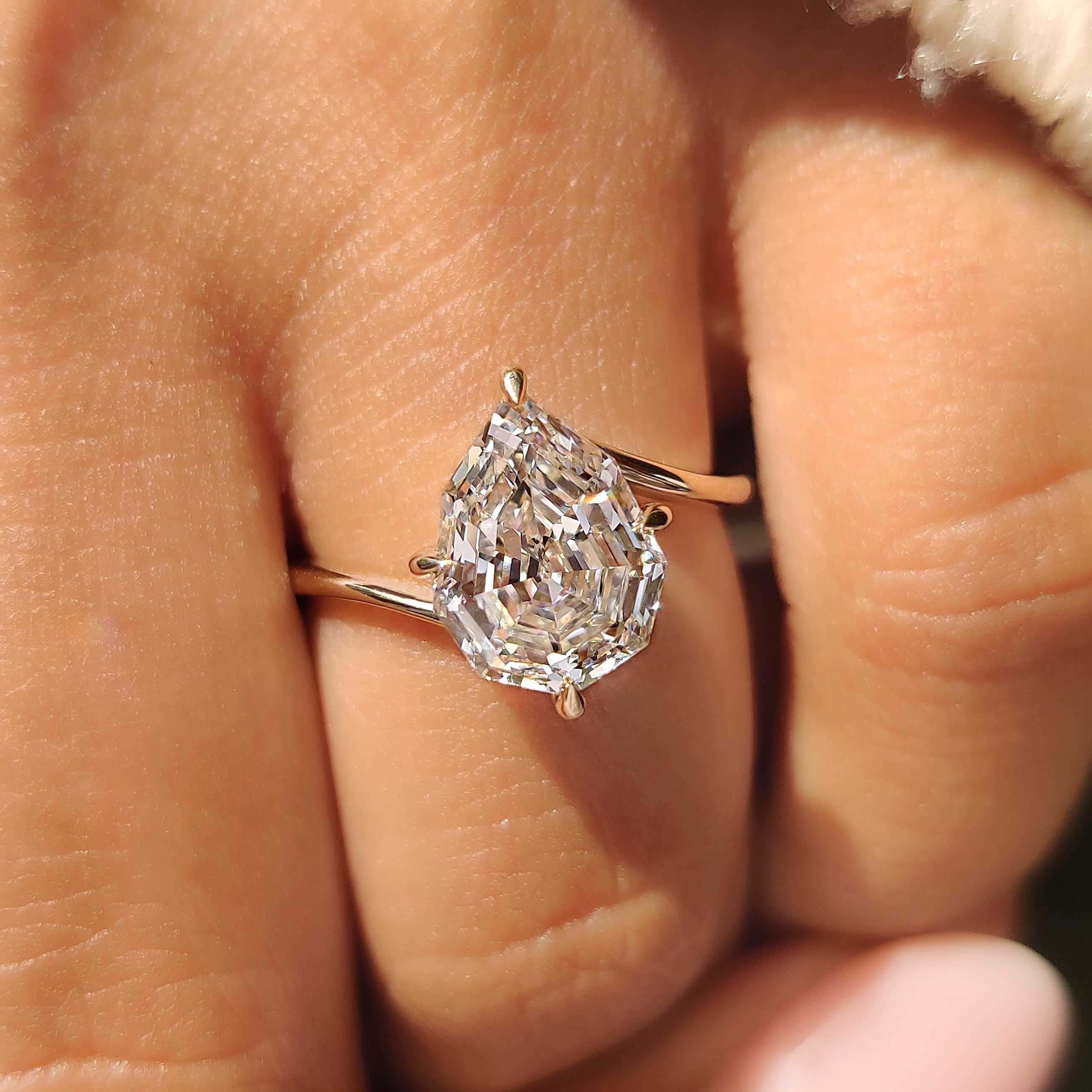Pear step cut diamond ring with four claw prongs.
