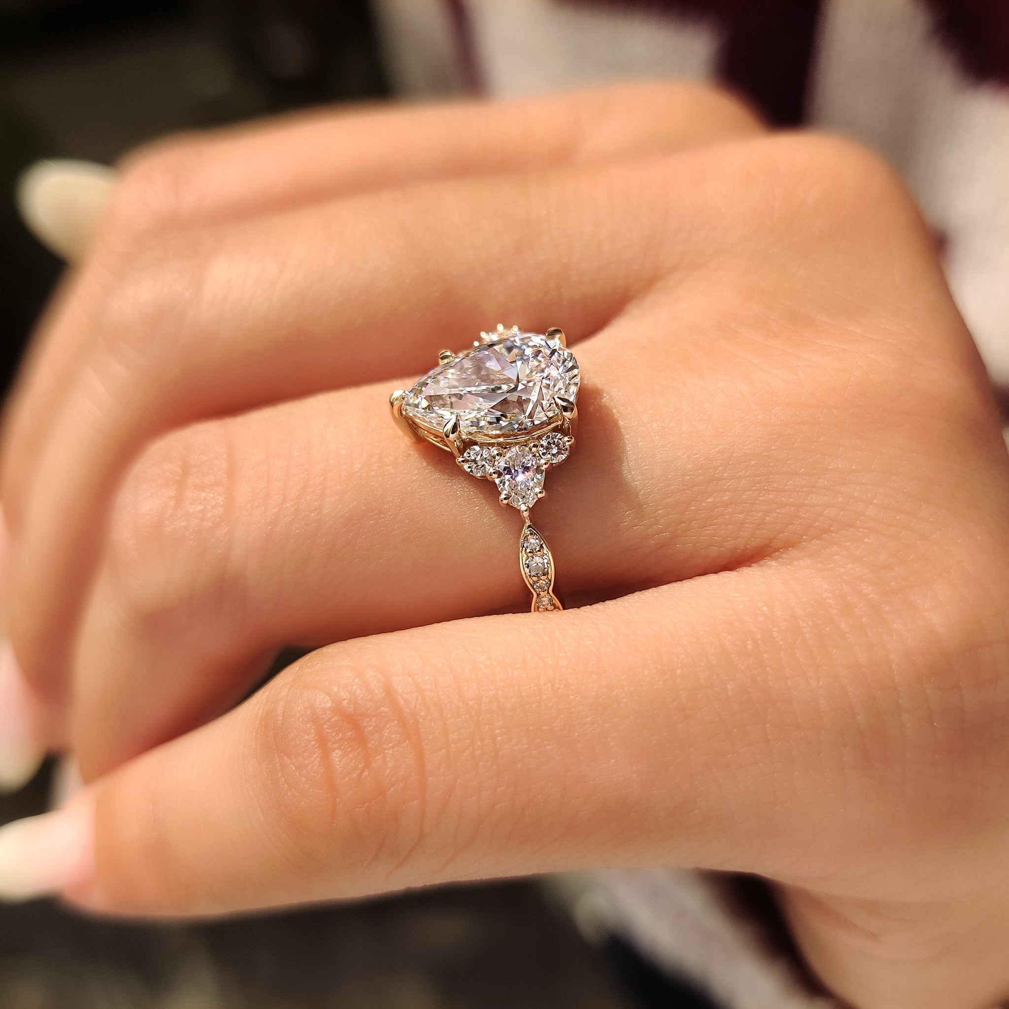 Pear ring with round side stones and prong set.
