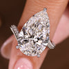 Pear diamond ring with double row round pave in a bypass setting and three claw prong.
