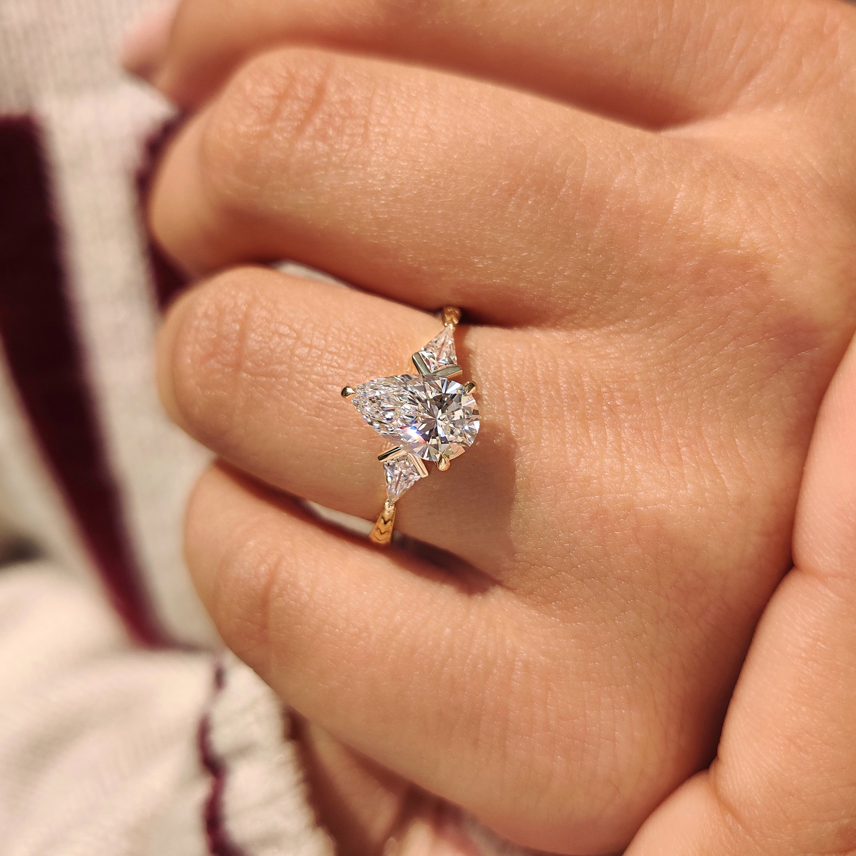 Tapered shank three diamond ring with pear center.
