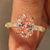 Pink oval diamond ring with round diamond accents.