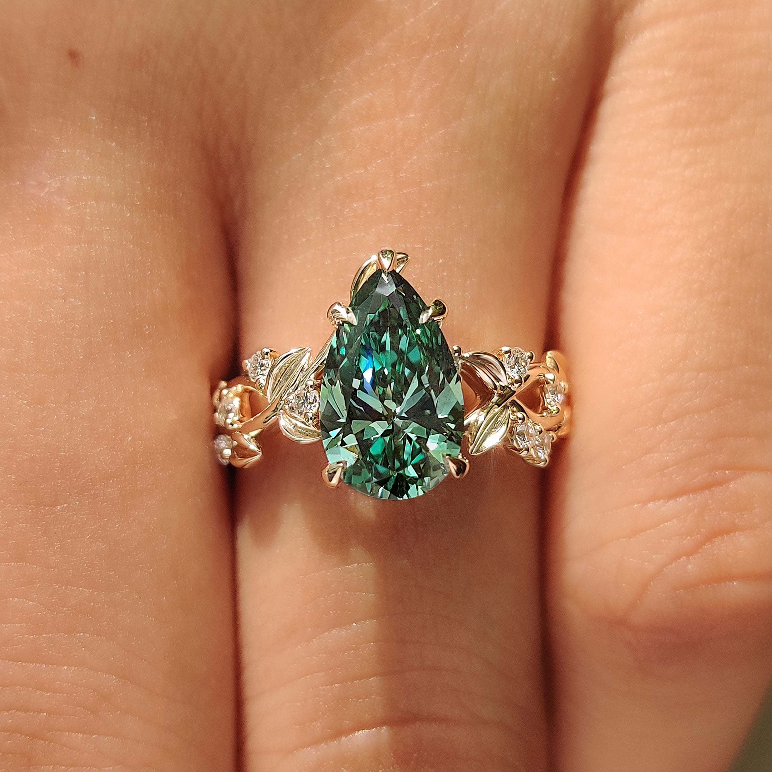 Pear shaped diamond ring with leaves and petals.
