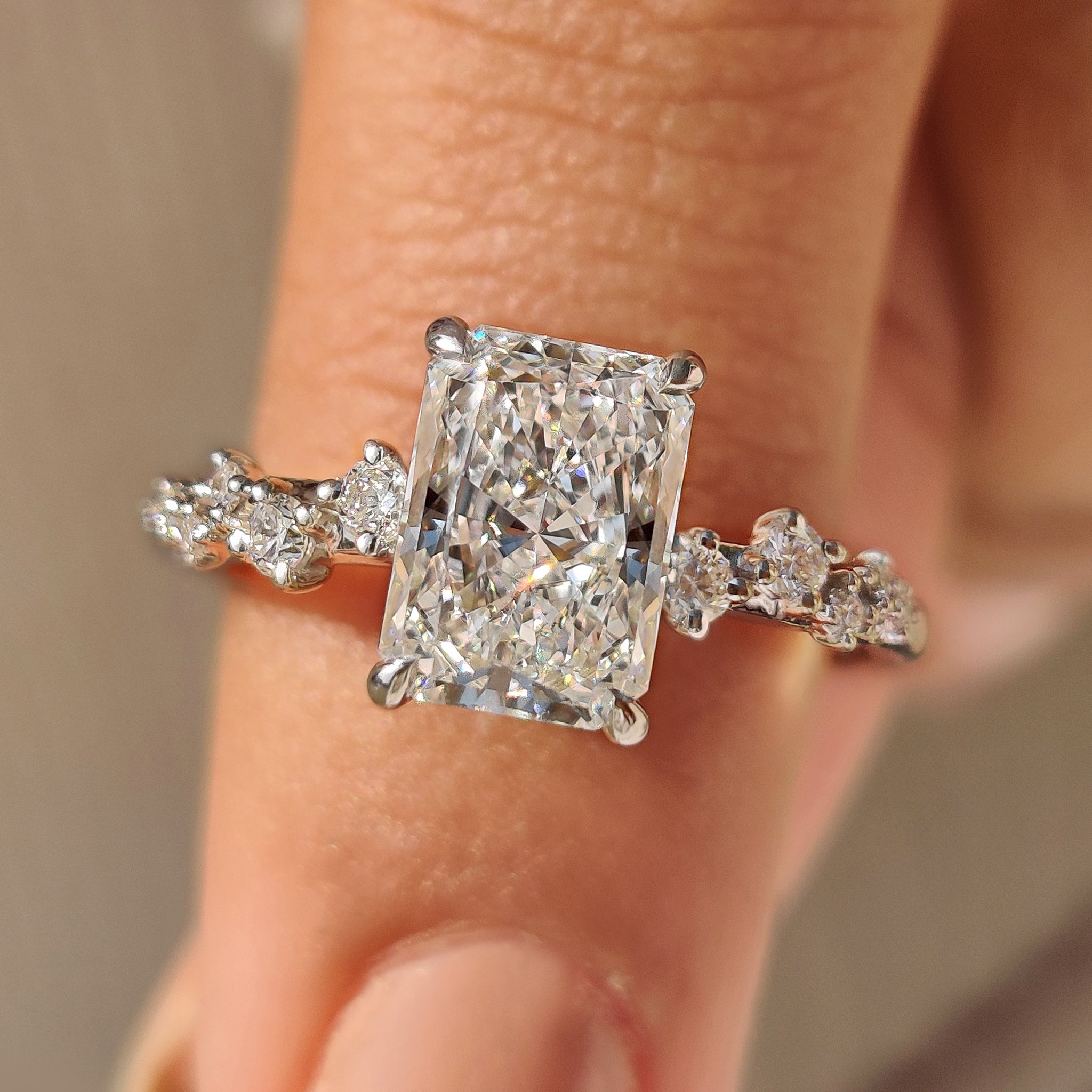 Radiant cut diamond ring with cluster setting and round diamonds.

