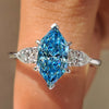 Blue dutch marquise center diamond with pear side stones in three stone ring
