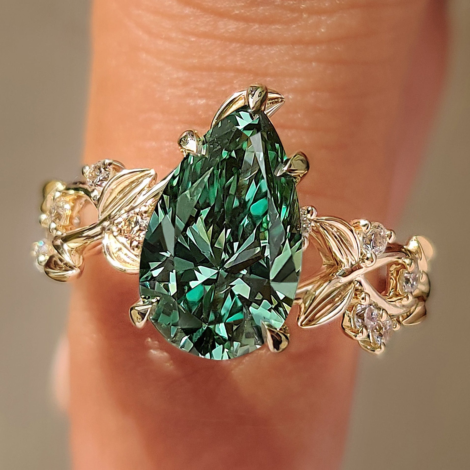 Green pear shaped diamond with round side stones.
