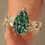 Green pear shaped diamond with round side stones.
