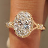 Oval center diamond bezel engagement ring with round side stones.
