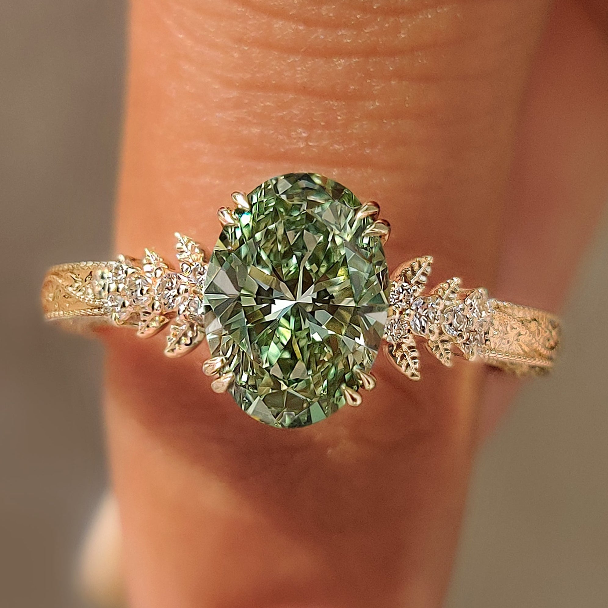 Green oval cluster ring with floral engraved band.
