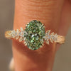 Green oval cluster ring with floral engraved band.
