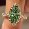 Green marquise diamond ring with marquise and round pave.
