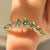 Half eternity wedding band with green round diamonds design
