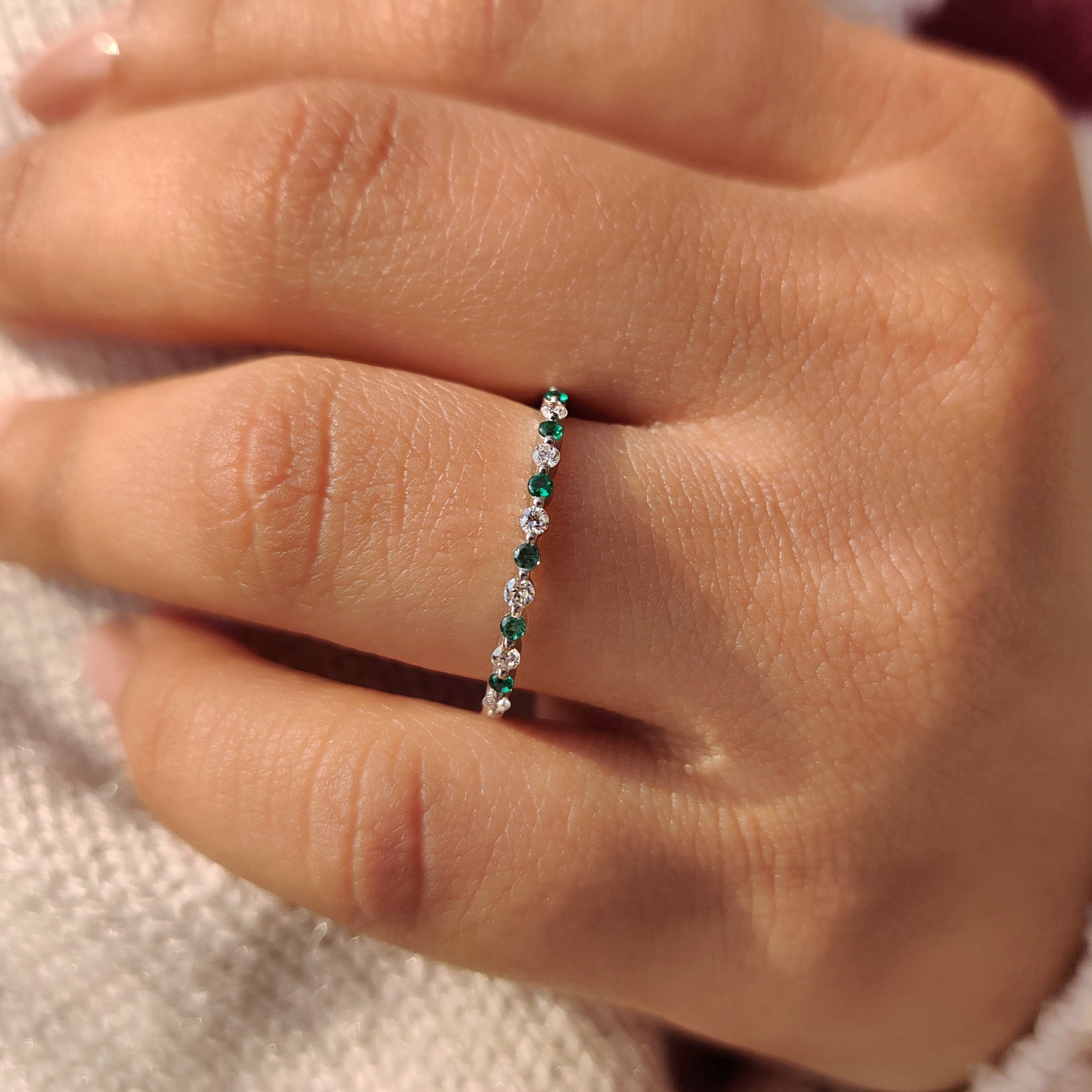 Half eternity band round diamonds and emerald gemstones.
