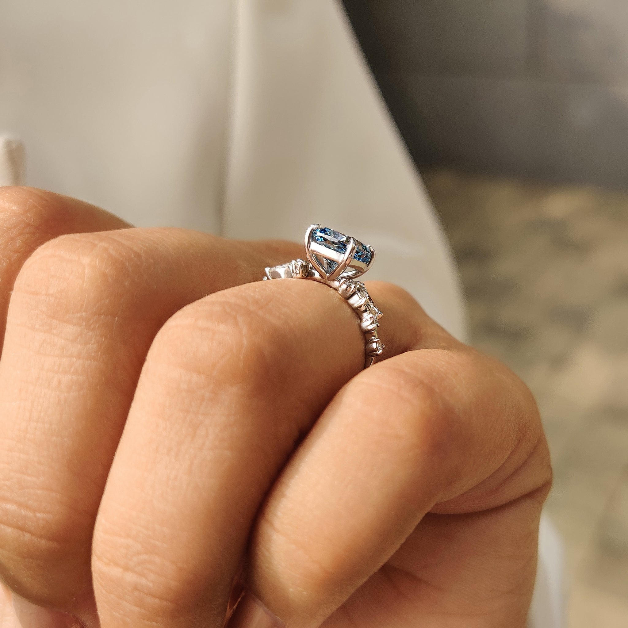 Lab grown cushion cut diamond ring with blue center stone.
