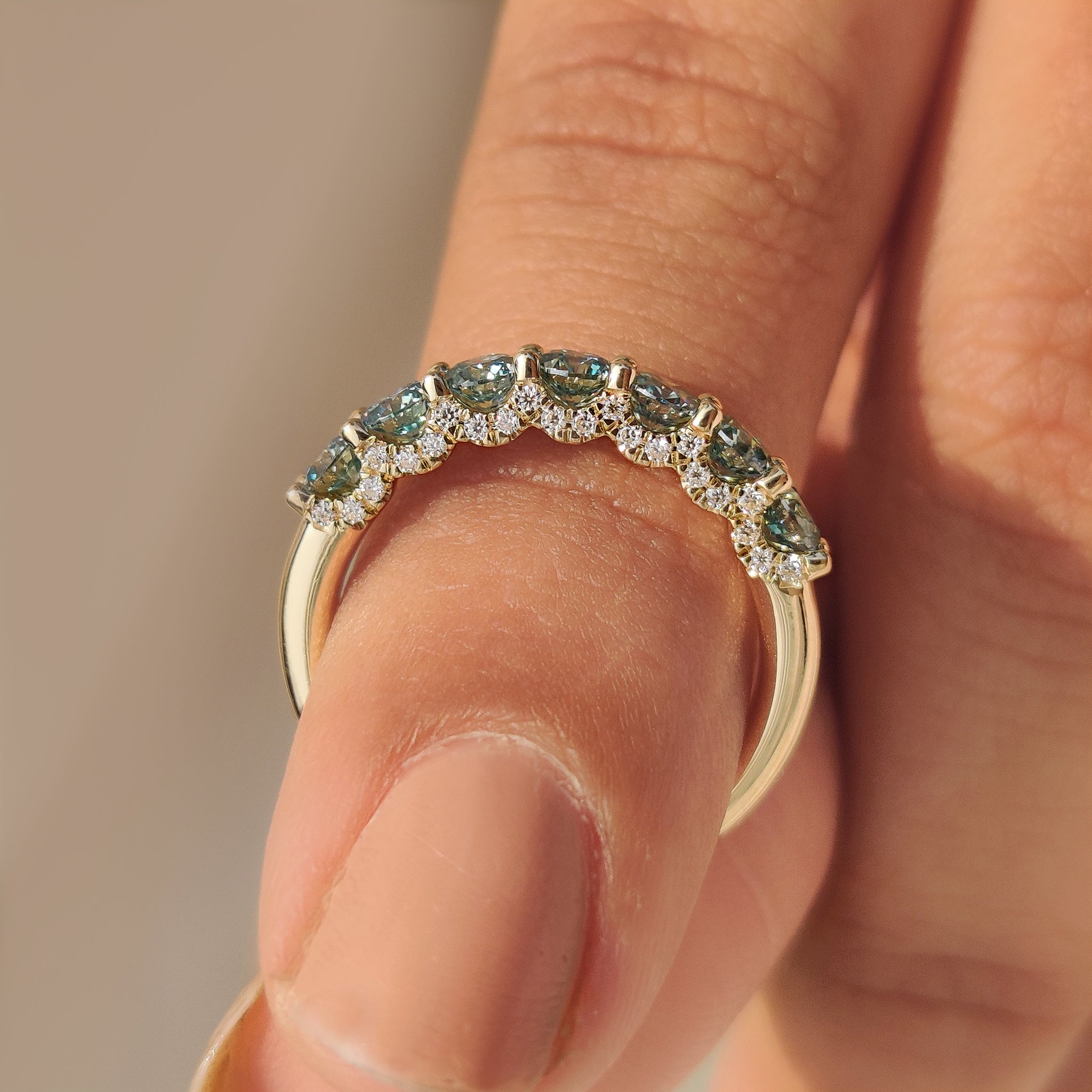 Half eternity band with blue moissanite and shared prong.
