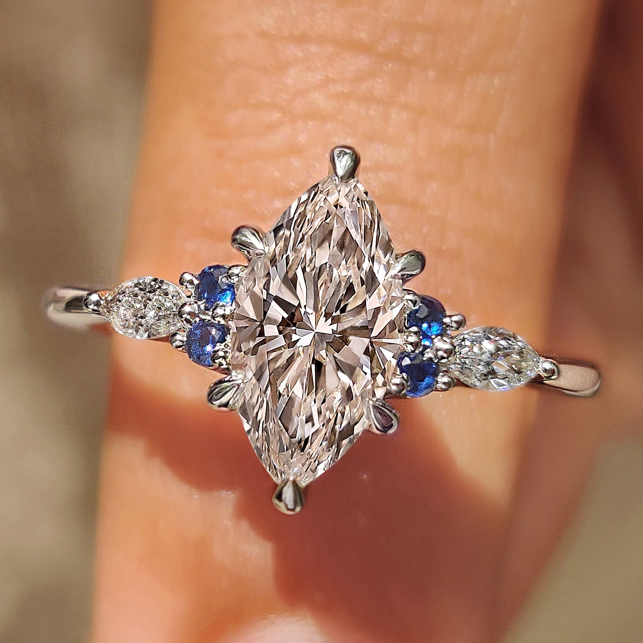 Marquise cut engagement ring with blue sapphire side stones

