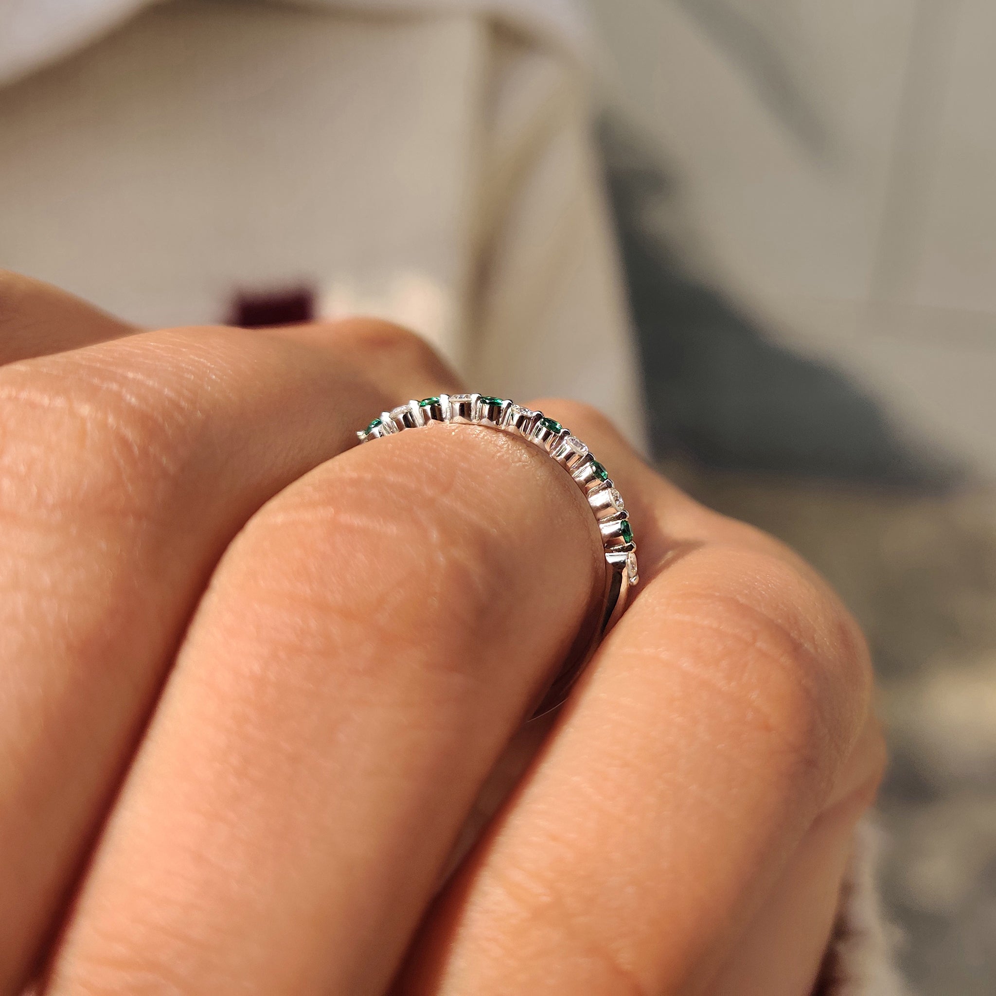 Half eternity band with emerald gemstones and round diamonds.
