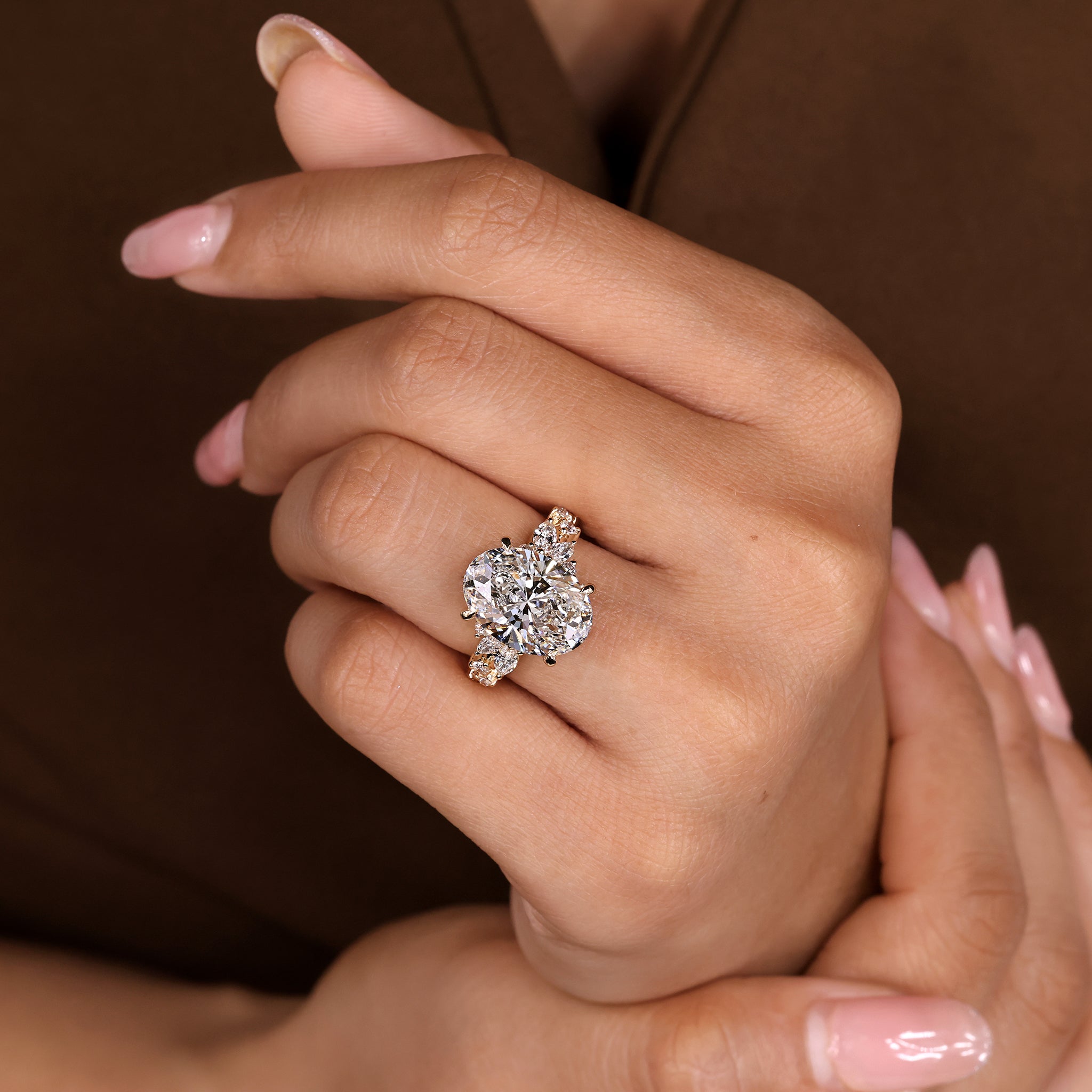Four claw prong oval cut diamond ring with elegant marquise and round cluster setting.
